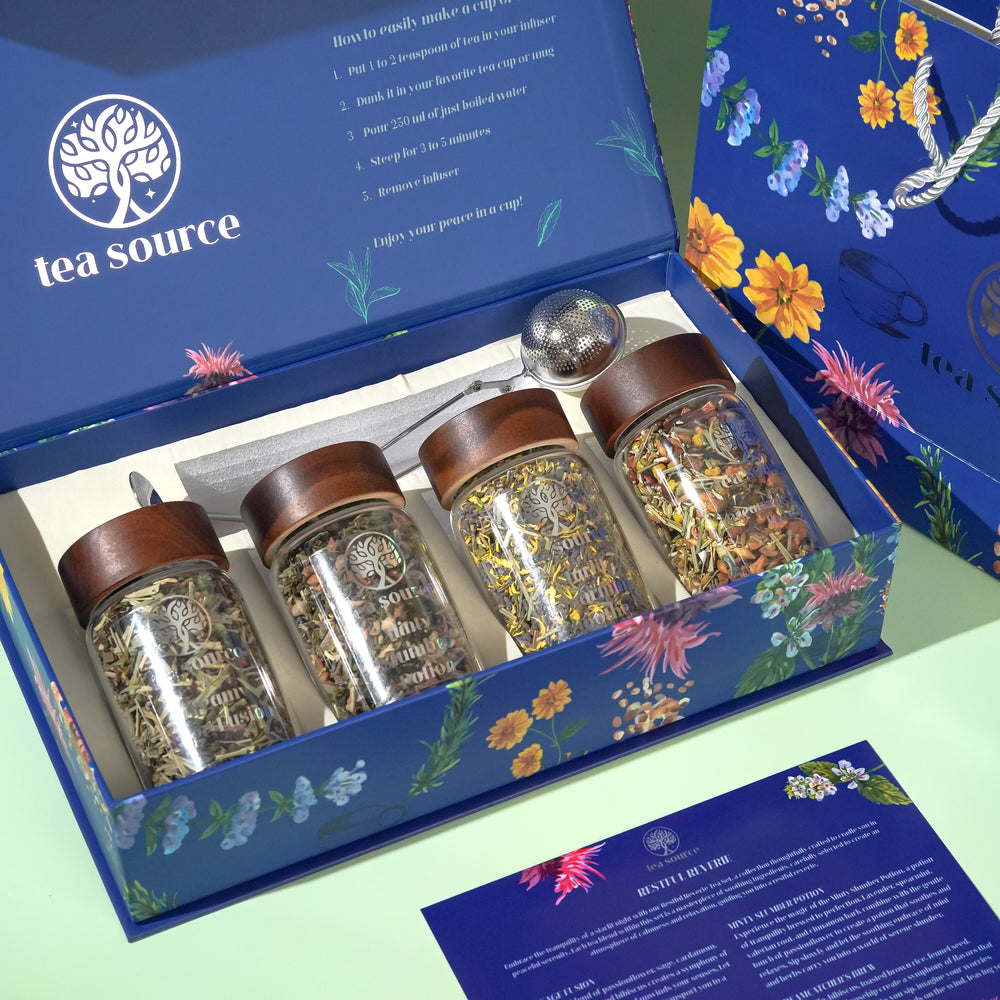 A tea set within a box with each jar labeled differently, displaying a floral design on the box's interior. The set is presented with a ballerina figure and a decorative tree, suggesting a premium, gift-ready package.