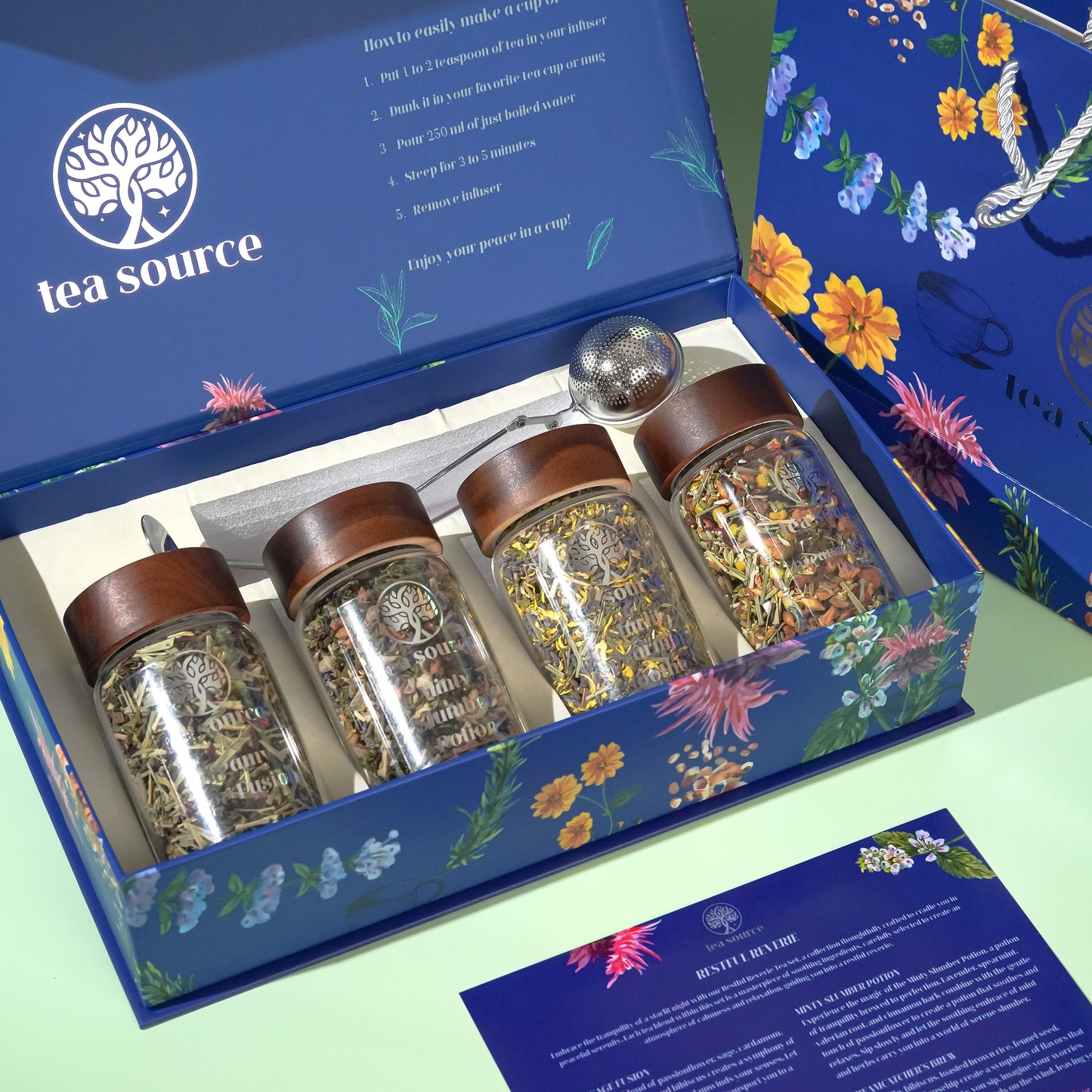 A tea set within a box with each jar labeled differently, displaying a floral design on the box's interior. The set is presented with a ballerina figure and a decorative tree, suggesting a premium, gift-ready package.